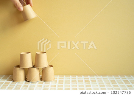 Pyramid stack of brown cup on desk. yellow background. business develop achievement growth concept 102347786