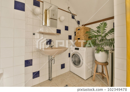 a laundry room with a washer, sink and plants in the corners on the wall next to the toilet a laundry room with a washer, sink and plants in the corners on the wall next to the toilet 102349478