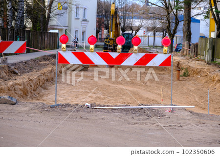 Road barrier at the road construction. Street construction with new communications. 102350606