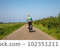 Older woman with camera bag biking on a electric bike in Sassenheim in the Netherlands. 102351211