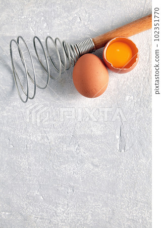 Two beige chicken eggs and a rare beater for beating 102351770