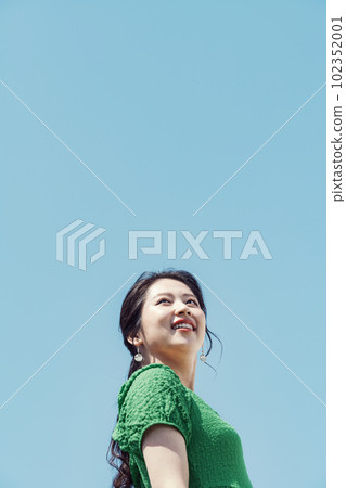 Outdoor portrait of a young woman wearing a green dress 102352001