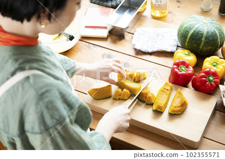 一個女人用菜刀切扭扭的南瓜 102355571