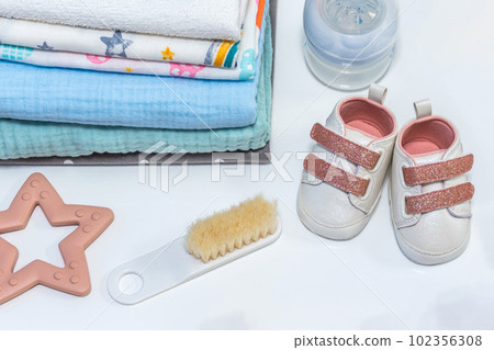 Baby girl pink shoes with other newborn baby accessories on white surface. Baby concept Baby girl pink shoes with other newborn baby accessories on white surface. Baby concept 102356308