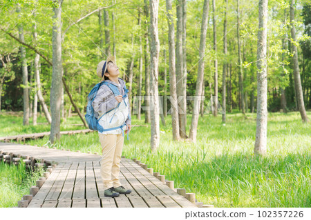 一位高級女性在新綠色中徒步旅行的照片 一位高級女性在新綠色中徒步旅行的照片 102357226