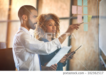 Coworkers, planning or brainstorming on tablet in modern office or paperwork, strategy conversation and sticky notes. Business people, documents and moodboard for idea and corporate company workplace 102362517