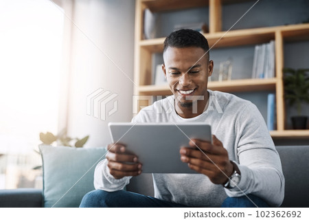 Relax, tablet and happy man on sofa reading social media meme, email or streaming video on subscription service. Happiness, internet and connection, male with smile on face and movie website on couch 102362692