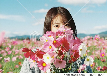 A woman holding a cosmos field bouquet with a smile 102363655