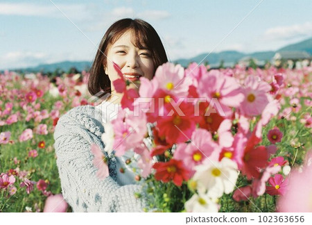 A woman holding a cosmos field bouquet with a smile A woman holding a cosmos field bouquet with a smile 102363656
