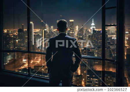 Back view of businessman looking at night view of big city from office window Back view of businessman looking at night view of big city from office window 102366527