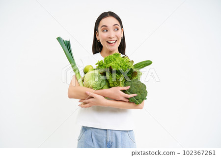 Portrait of smiling korean woman, hugs her vegetables, likes eating raw food, vegetarian enjoys nutritious diet, white background Portrait of smiling korean woman, hugs her vegetables, likes eating raw food, vegetarian enjoys nutritious diet, white background 102367261