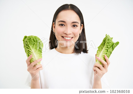 Happy korean woman vegetarian, smiling and showing cabbage, eating lettuce on diet, leads active lifestyle, white background 102368038