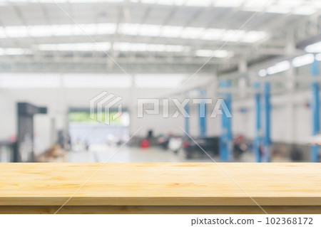 Empty wood table top with car service centre auto repair workshop blurred background 102368172