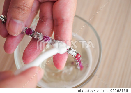 Jeweller hand cleaning and polishing vintage jewelry red ruby bracelet closeup Jeweller hand cleaning and polishing vintage jewelry red ruby bracelet closeup 102368186
