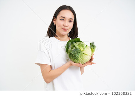 Lovely smiling woman, holding cabbage, posing with lettuce against white background Lovely smiling woman, holding cabbage, posing with lettuce against white background 102368321