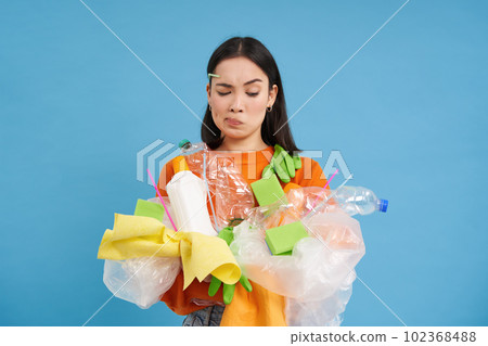 Caring for nature. Young woman holding plastic bottles and waste. Volunteers compiled garbage and carry it to recycling. blue isolated background 102368488