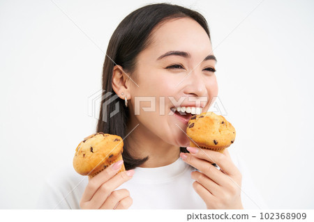 Close up portrait of happy, beautiful smiling woman, eating pastry cupcake, likes bakery, white background 102368909