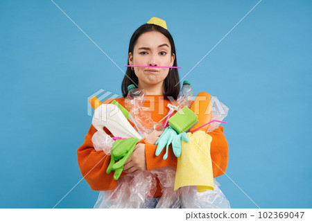 Environment and ecology. Portrait of asian woman holding plastic waste, pile of garbage, blue background Environment and ecology. Portrait of asian woman holding plastic waste, pile of garbage, blue background 102369047