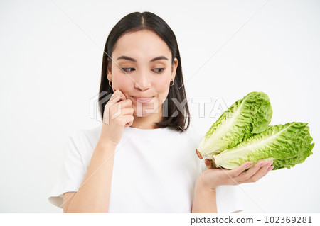 Nutrition and healthy food. Smiling japanese woman shows cabbage, fresh lettuce, isolated on white background 102369281