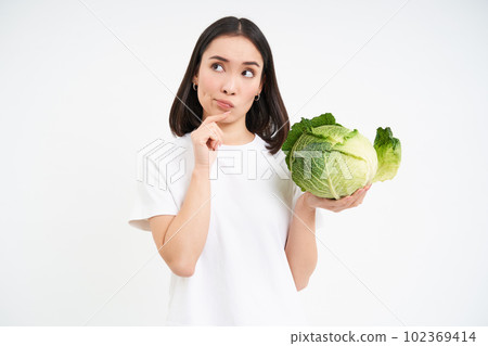 Girl with thinking face, holding lettuce, standing pensive with cabbage, isolated on white background 102369414