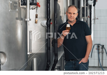 brewer at a modern brewery with glass of beer 102371213