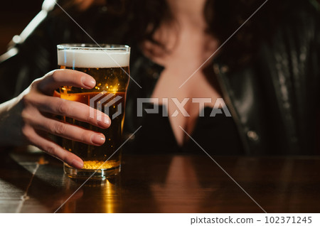 woman with big breasts holds a glass of beer lager with foam in her hand woman with big breasts holds a glass of beer lager with foam in her hand 102371245