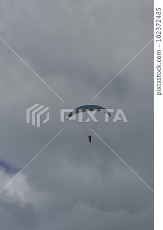A person paragliding on a cloudy day 102372485