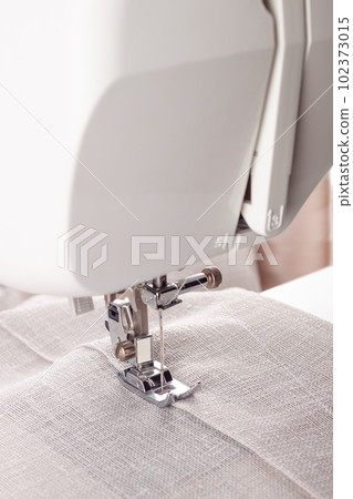 Modern sewing machine presser foot with linen fabric and thread, closeup Modern sewing machine presser foot with linen fabric and thread, closeup 102373015