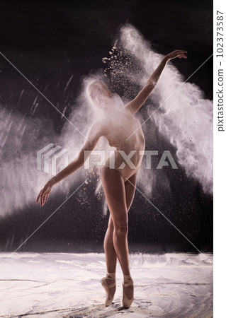 Ballerina on a black background with a cloud of white flour. 102373587