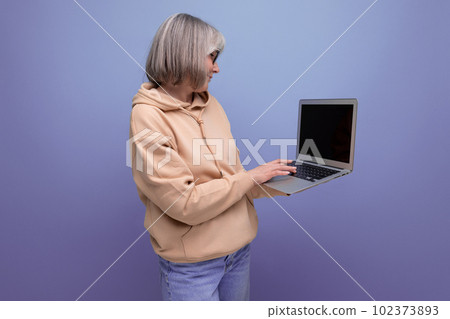 fashionable 60s business woman grandmother with gray hair working using laptop on studio background fashionable 60s business woman grandmother with gray hair working using laptop on studio background 102373893