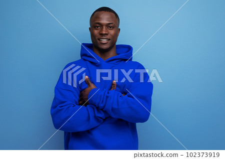 close-up of a serious pensive american young guy in a sweatshirt with a hood with his arms crossed 102373919