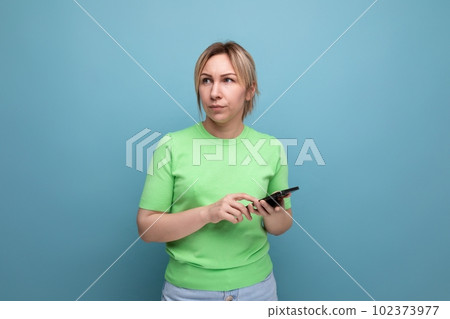 indignant attractive blond girl with gadgets in her hand on a blue background with copy space indignant attractive blond girl with gadgets in her hand on a blue background with copy space 102373977