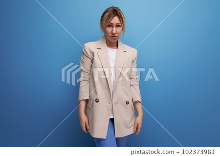 blond millennial woman in a beige jacket posing on a blue background copy space blond millennial woman in a beige jacket posing on a blue background copy space 102373981