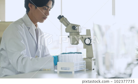 Male scientist observing with a microscope Male scientist observing with a microscope 102377735
