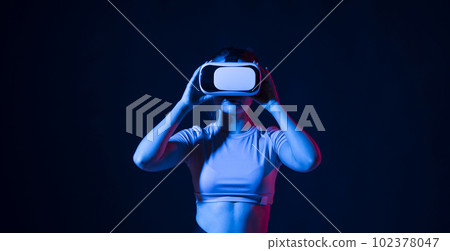 Woman enjoying a VR experience. Woman with VR headset touching invisible screen. Future technology concept. 102378047