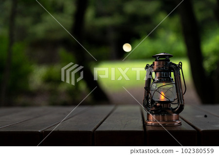 Antique lantern glowing in the woods 102380559