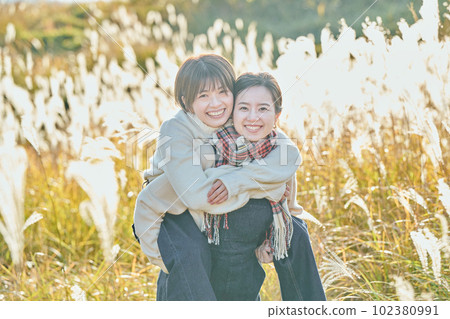 一個好年輕女人和她的朋友在蒲葦的背景下背著一個朋友 一個好年輕女人和她的朋友在蒲葦的背景下背著一個朋友 102380991