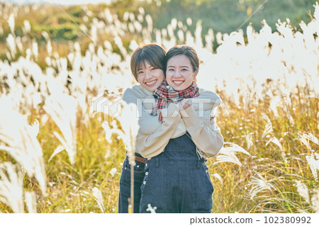 Young woman and her friend hugging against the background of pampas grass 102380992