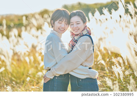 Young woman and her friend hugging against the background of pampas grass 102380995