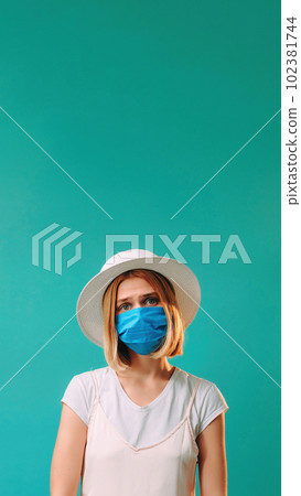 Pandemic hygiene. Grippe prevention. Upset dissatisfied woman in white and medical mask flu epidemic isolated on turquoise copy space background. 102381744