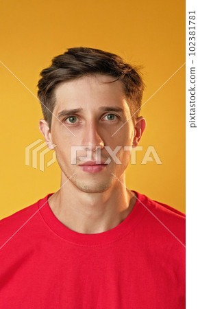 Serious expression. Strict male portrait. Handsome unsmiling guy with attentive determined face isolated on yellow background. 102381781