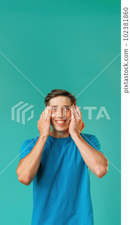 Successful achievement. Amazed idea. Excited handsome guy in blue holding hands head expressing amazement isolated on turquoise copy space background. 102381860