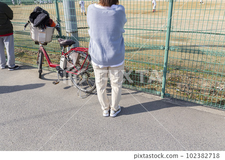 一位母親透過柵欄觀看青少年棒球比賽 102382718