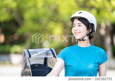 一個戴著頭盔騎自行車的女人。 102382791