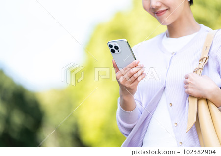 A woman operating a smartphone outdoors (parts model) A woman operating a smartphone outdoors (parts model) 102382904