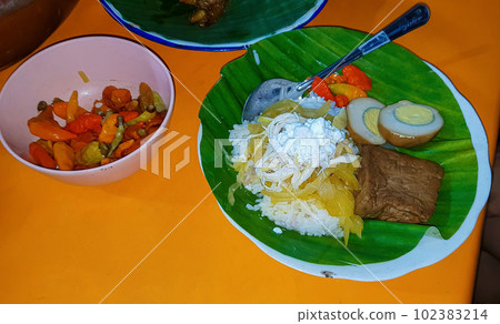 Indonesian food Liwet Rice. A Traditional javanese Rice Served with Chicken, Tofu, Tempeh, vegetable, Chili and Broad Beans in a plate with banana leaf Indonesian food Liwet Rice. A Traditional javanese Rice Served with Chicken, Tofu, Tempeh, vegetable, Chili and Broad Beans in a plate with banana leaf 102383214