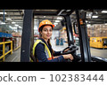 Portrait of smiling woman working with a forklift in a warehouse. Generative AI 102383444