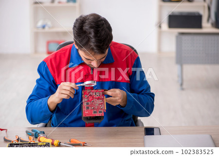 Young male repairman repairing computer Young male repairman repairing computer 102383525