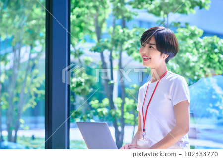 An IT engineer operating a computer in front of the fresh greenery in the office courtyard Photo courtesy of LINK FOREST 102383770