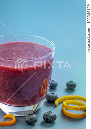 Glass mug of blueberry smoothie on blue background 102384199